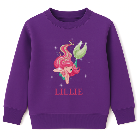 Girls purple sweatshirt featuring a pink-haired mermaid surrounded by stars with personalised name “Lillie” printed underneath.