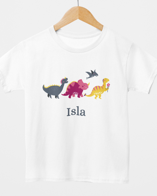Personalised girls dinosaur white t-shirt with custom name Isla, displayed on a wooden hanger with cute colourful dinosaur design.
