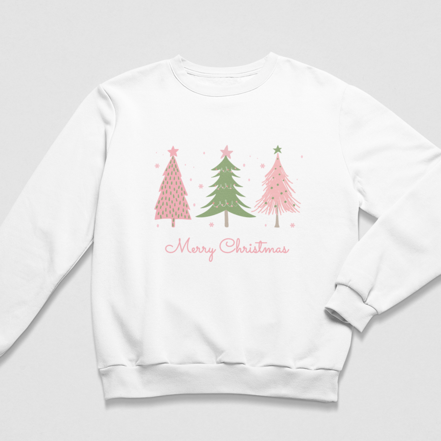 A kids white crewneck sweatshirt featuring a graphic of three Christmas trees in pink and green with the text 'Merry Christmas' written below in pink cursive, displayed on a light grey background.