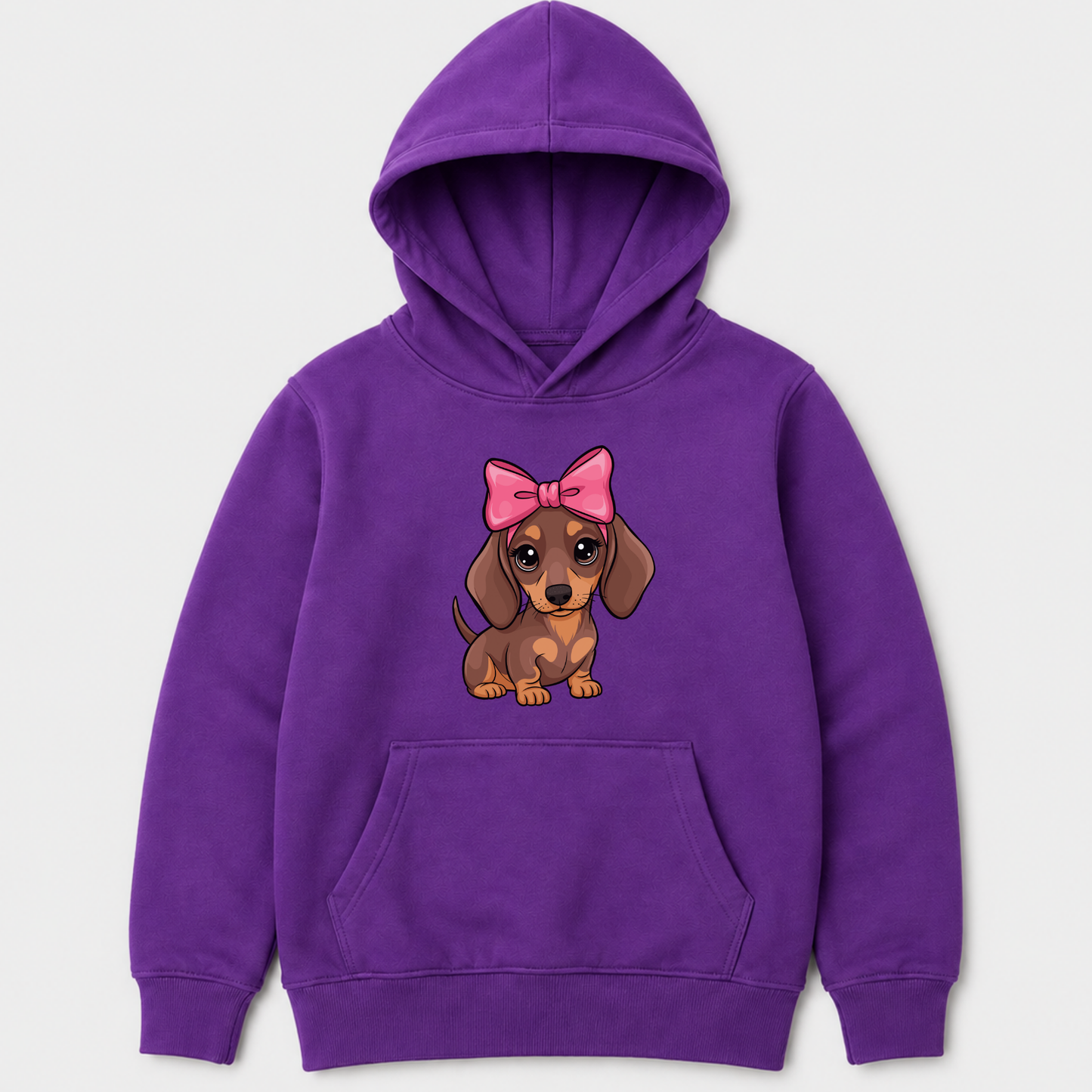 A purple kids pullover hoodie featuring a cartoon dachshund graphic on the chest, wearing a pink bow. The hoodie has a front kangaroo pocket and ribbed cuffs and hem, shown against a light gray background.