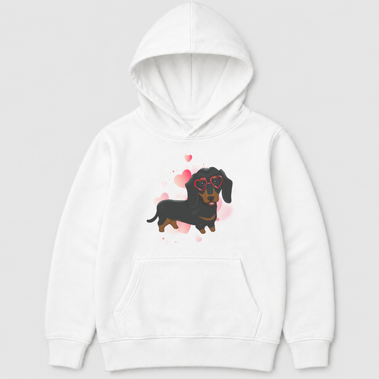 Kids white pullover hoodie featuring a black and tan dachshund wearing red heart-shaped glasses, surrounded by soft pink hearts.