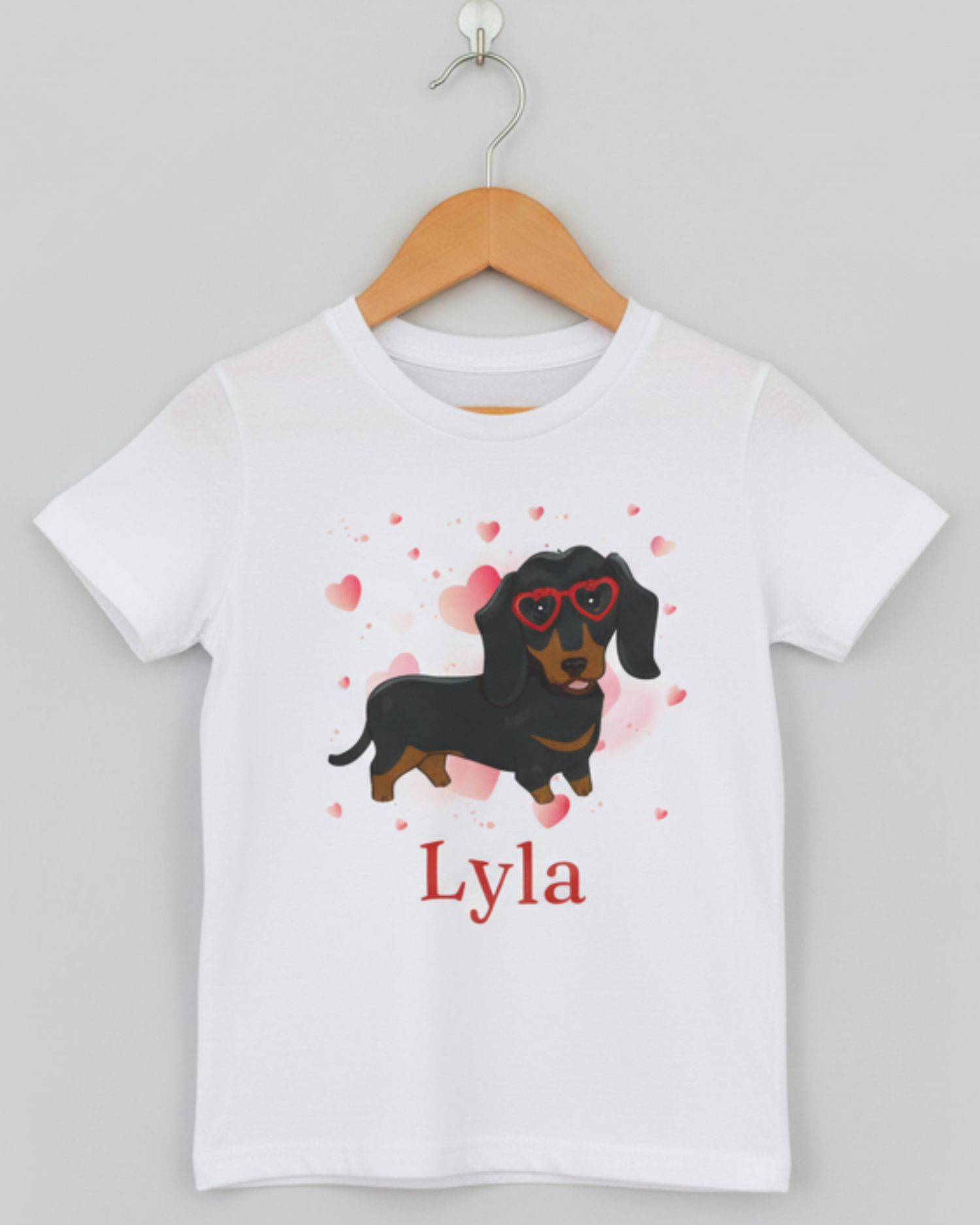 Personalised white kids t-shirt with dachshund hearts design and custom name on wooden hanger