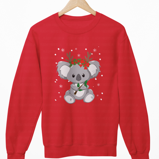 Red sweatshirt with a koala bear design wearing reindeer antlers and a bow tie on a wooden hanger