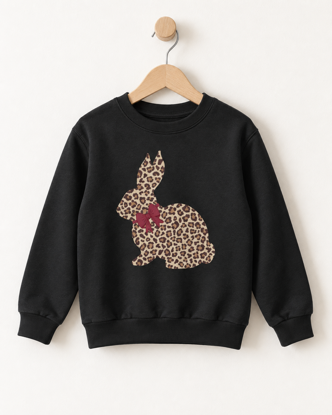 Black girls’ sweatshirt featuring a leopard-print bunny with a burgundy bow, displayed on a wooden hanger.