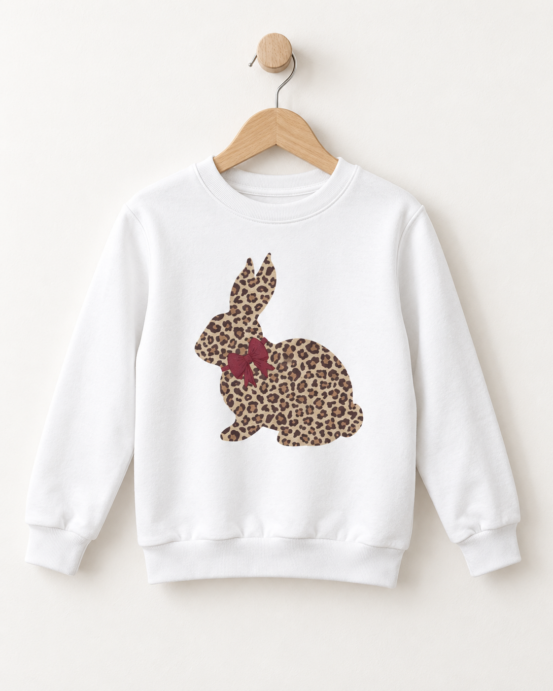 White girls’ sweatshirt featuring a leopard-print bunny with a burgundy bow, displayed on a wooden hanger.