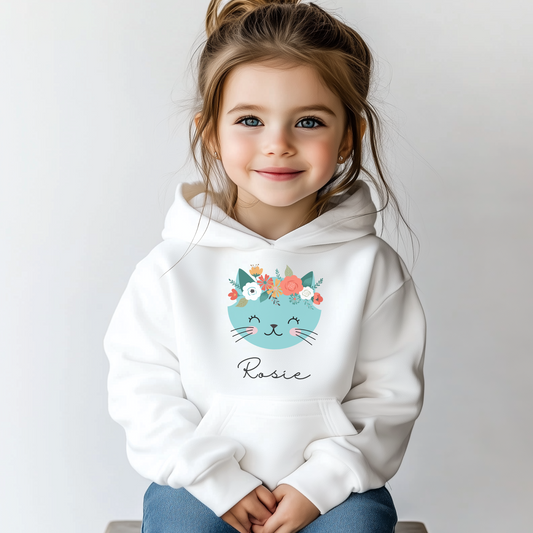 “Smiling girl wearing a white personalised hoodie with a blue floral cat design and the name Rosie printed underneath.”