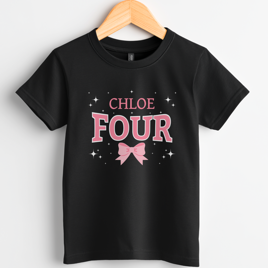 Kids t-shirt on a wooden hanger with 'Four' pink and white text and pink bow and stars with personalised name.