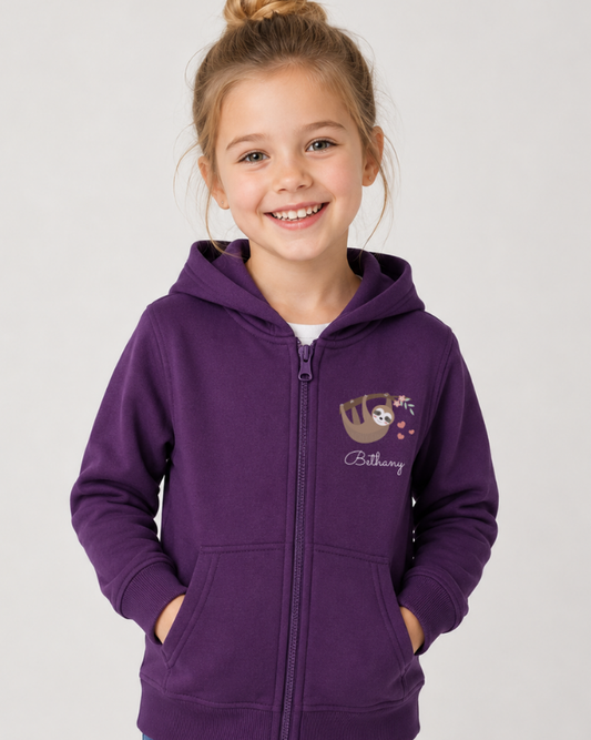 Young girl wearing a purple hoodie with a hanging sloth and name underneath motif - studio setting.