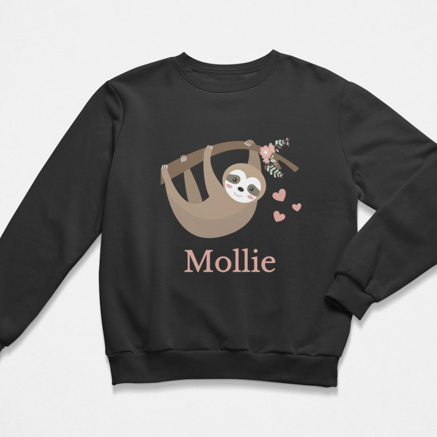 A kids black crewneck sweatshirt featuring a cartoon sloth hanging in a tree branch with a small bouquet and pink hearts, with the name 'Mollie' printed below in a dusty pink font.
