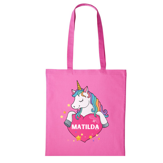 Girl pink cotton tote bag with a white unicorn holding a pink heart featuring a custom name inside the heart, surrounded by stars.