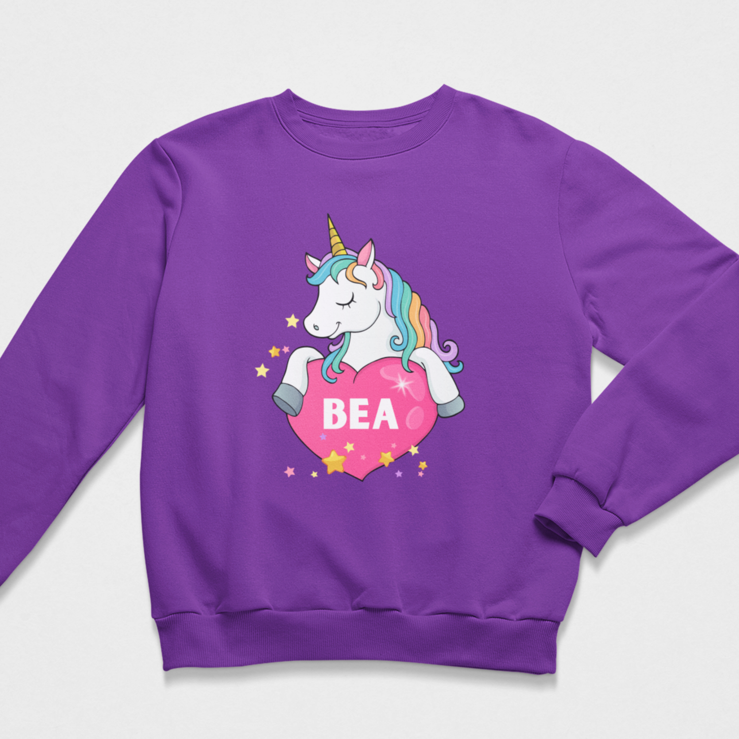 Girls’ purple personalised sweatshirt featuring a rainbow-maned unicorn resting above a pink heart with the name Bea.