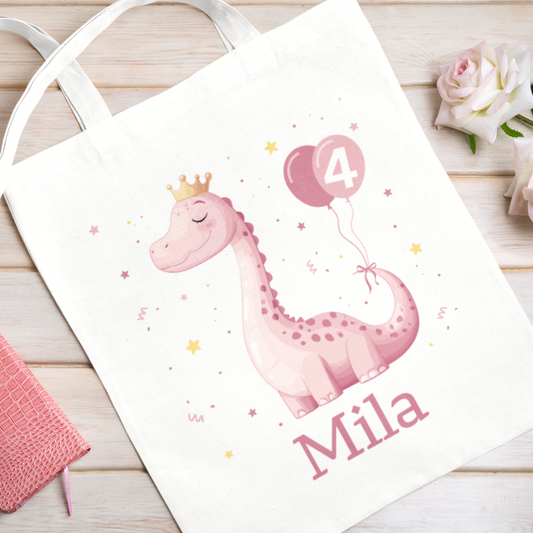 Kids white cotton tote bag featuring a pink dinosaur with a crown and birthday balloon marked "4", personalised with the name.