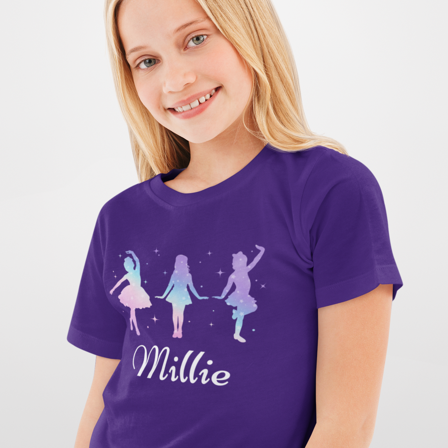 Girl wearing a purple personalised dance t-shirt featuring three pastel silhouette dancers with stars and the name “Millie” printed below.
