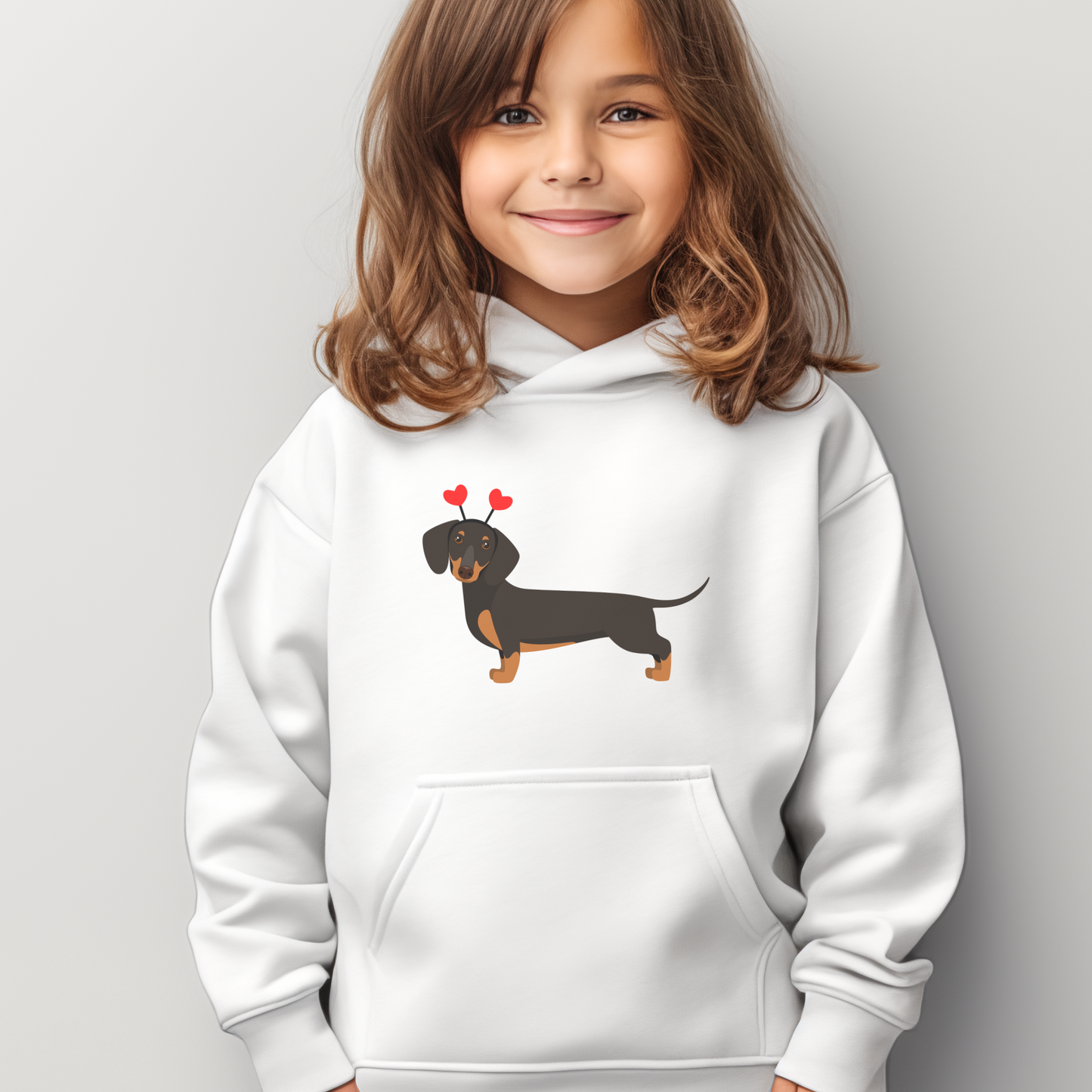 Girl wears a white hoodie with a printed cute black and tan dachshund dog.