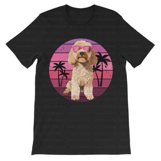 Kids black t-shirt featuring a Cockapoo dog with pink sunglasses in front of a retro pink sunset and palm tree background. 