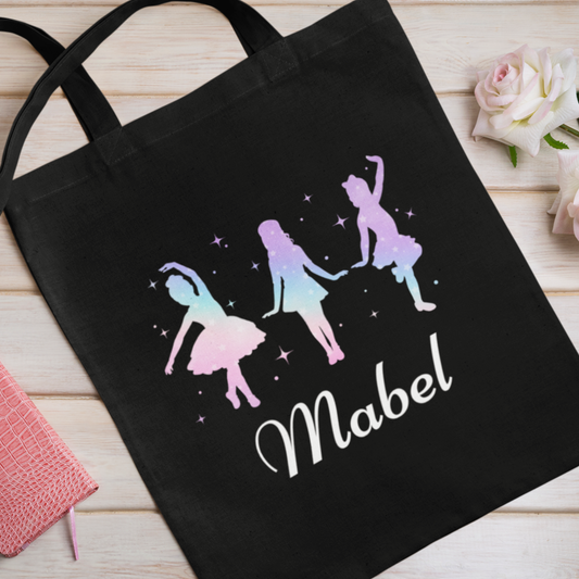 Black tote bag with colorful ballerina design and 'Mabel' text on a wooden surface.