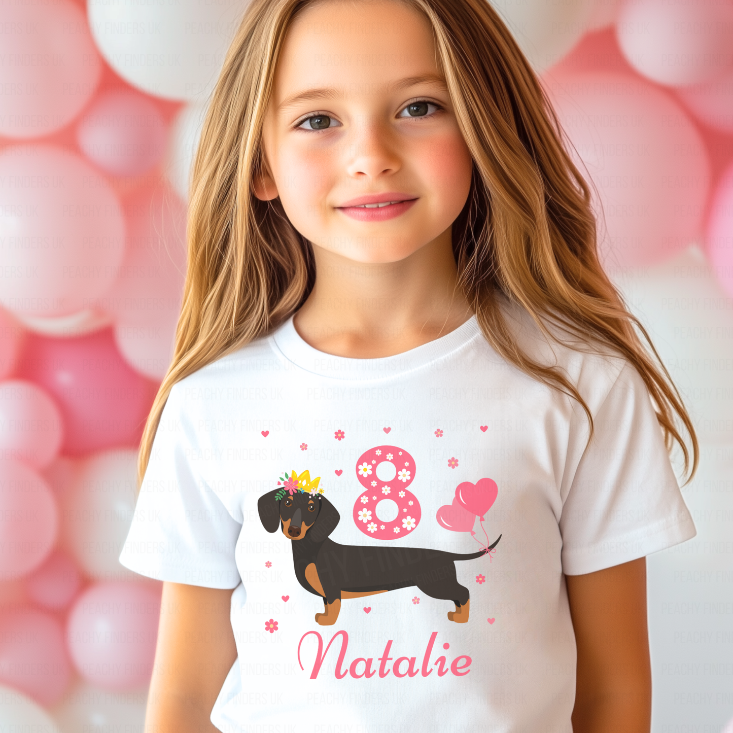 A girl wearing a white t-shirt with a dachshund design and personalised text that reads 'Natalie'. The t-shirt also features numbers '8' with pink hearts and flowers.