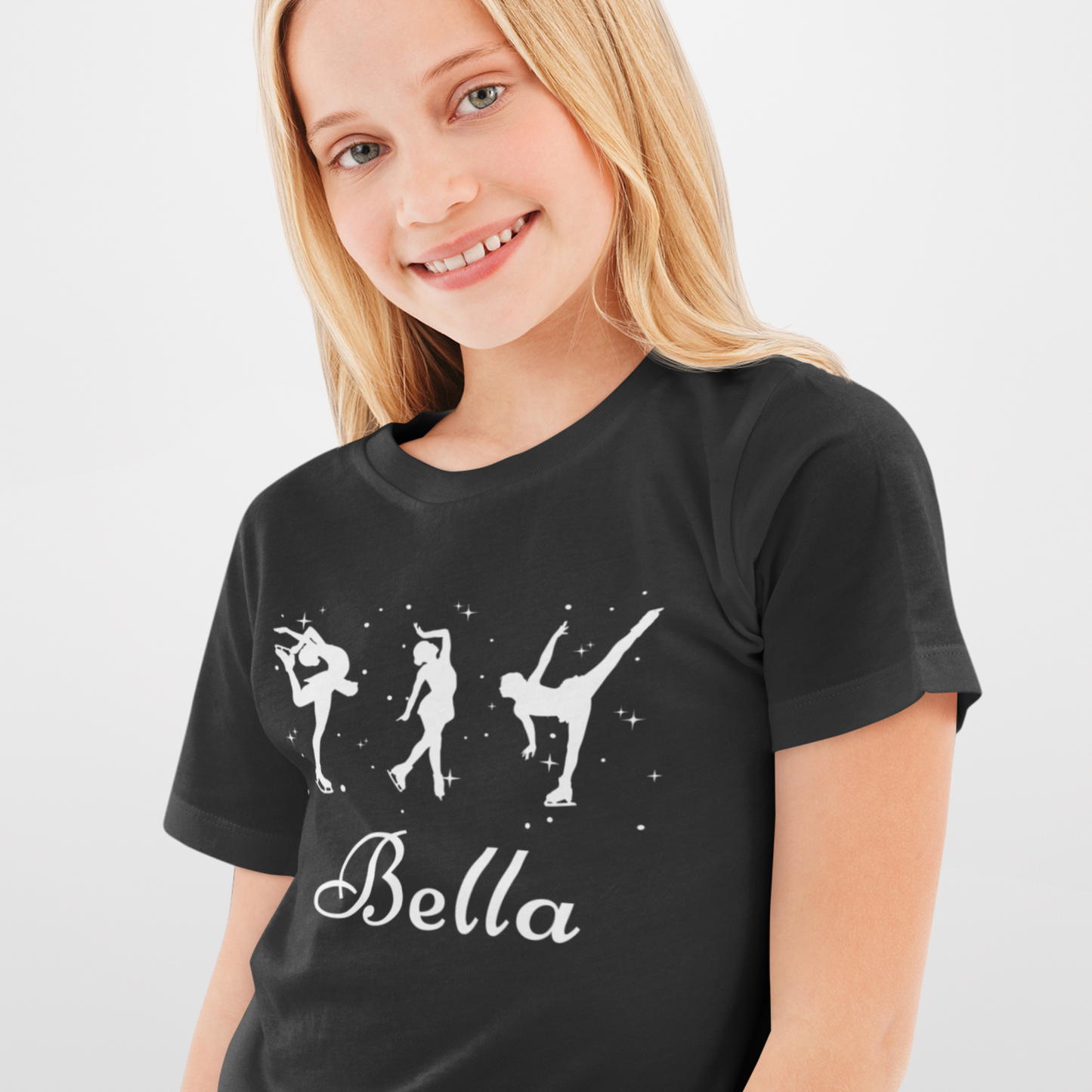 Child wearing a black personalised ice skater t-shirt featuring three white figure skating silhouettes with stars and the name “Bella” printed underneath.