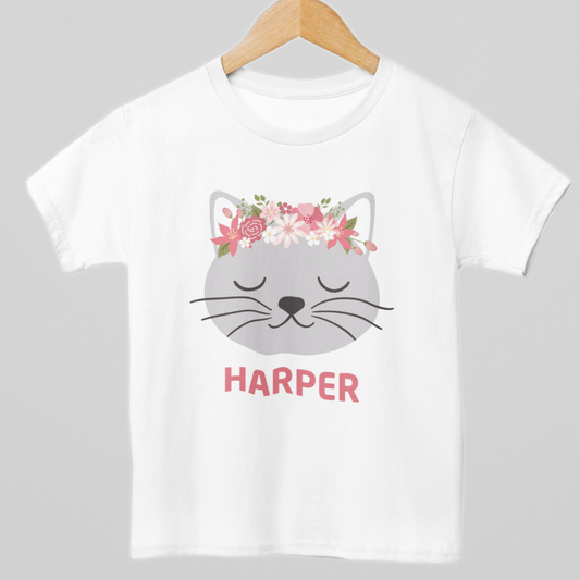 Girls white cotton t-shirt, styled on a wooden hanger - personalised floral cat design with custom name printed under a grey kitten face with pink flower crown