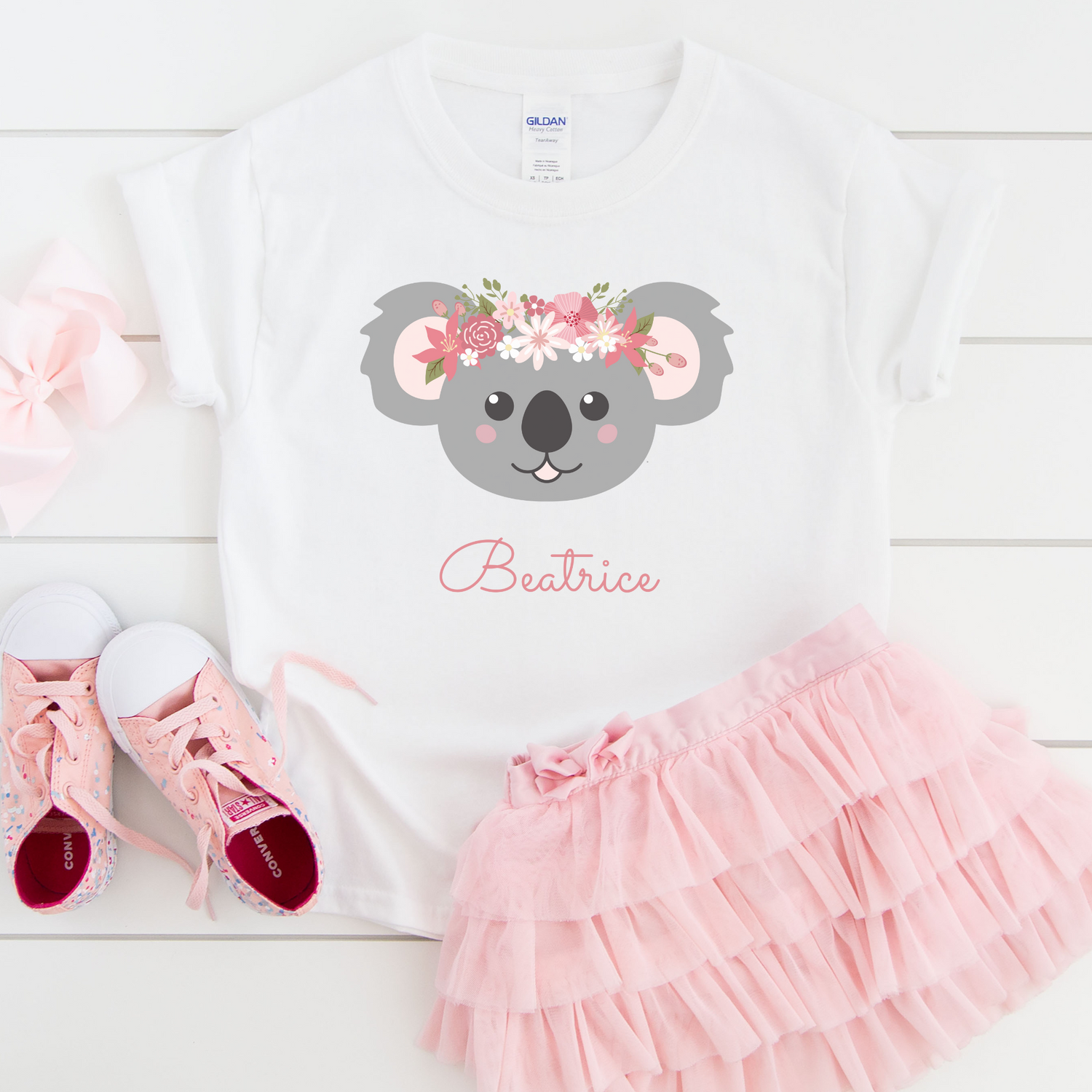 Kids pink tutu, pink shoes and hair bow with a white t-shirt lay flat with a printed koala and the name Beatrice underneath design.