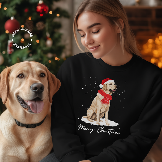 Woman wears black Christmas jumper featuring a golden Labrador wearing a Santa hat and red festive scarf with snowy background and “Merry Christmas” text.