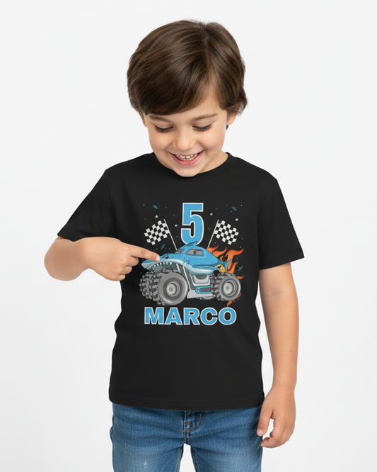 Happy boy wearing personalised 5th birthday monster truck t-shirt with name Marco, black birthday shirt with blue truck design, studio photo