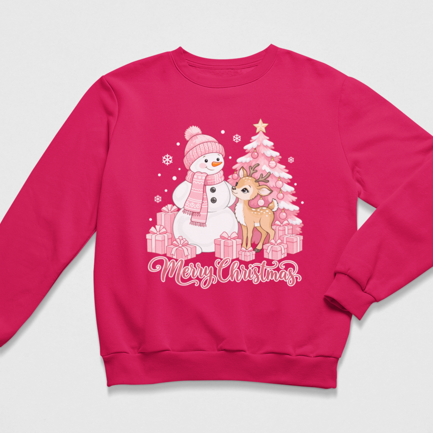 Flat lay of a hot pink kids' Christmas crewneck sweatshirt featuring a pink holiday graphic of a snowman in a winter hat and scarf next to a baby deer, a pink Christmas tree with gifts, and "Merry Christmas" script lettering.