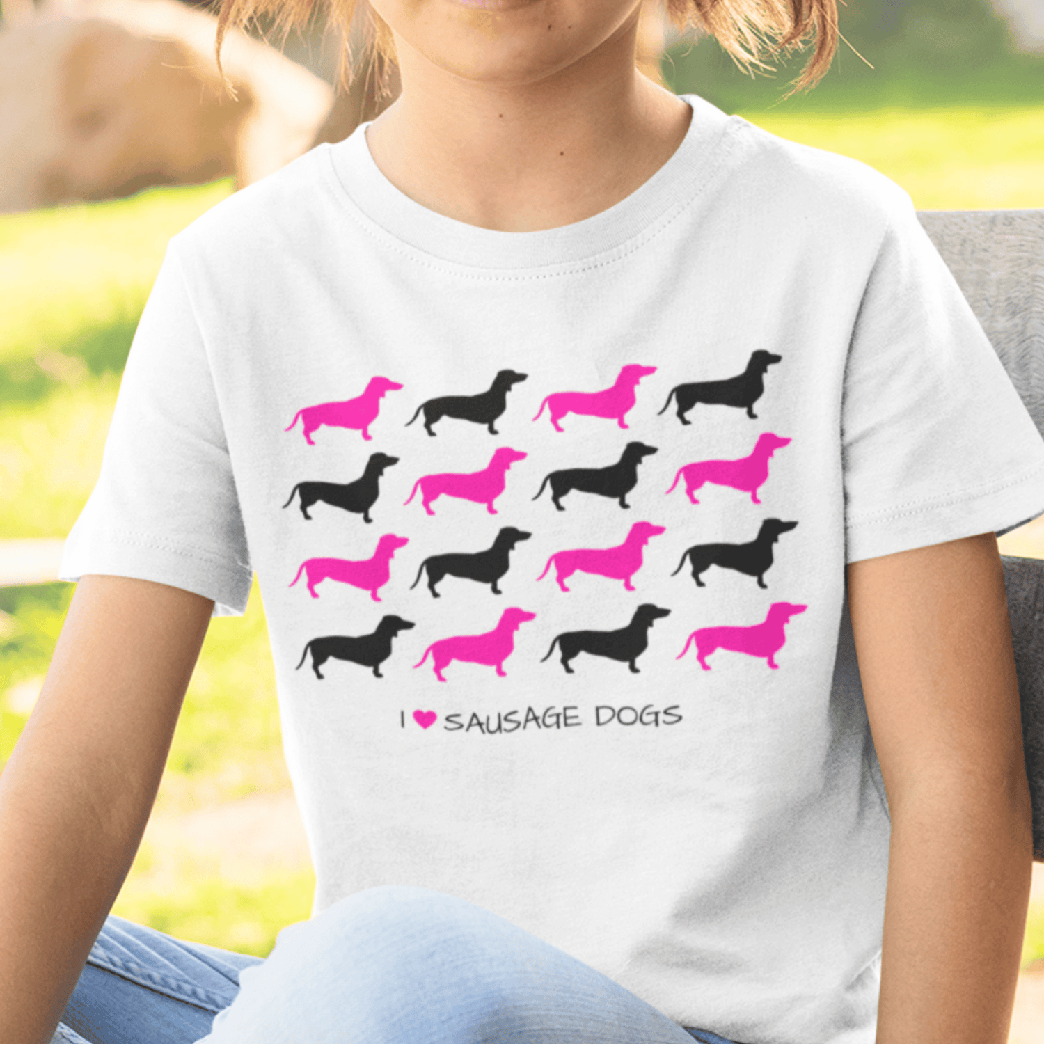 Girl wears white short sleeved t-shirt with black and pink Sausage Dogs