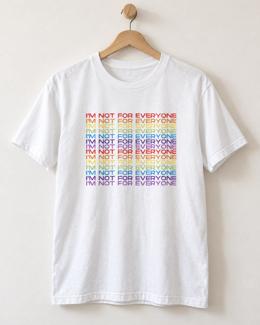 A white short-sleeve crewneck t-shirt hanging on a wooden hanger against a light beige wall. The front of the shirt features a stacked graphic print reading 'I'M NOT FOR EVERYONE' repeated in a rainbow color gradient.