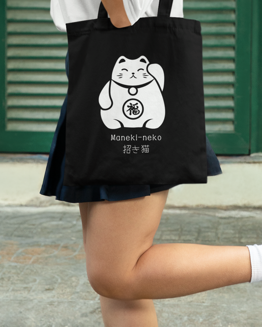 Girl carries a black cotton tote bag with white Maneki-neko Japanese Lucky Cat design and text printed on the front.