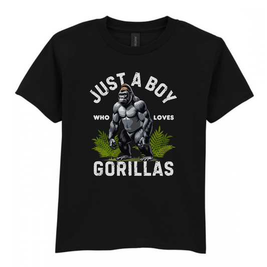 Kids black cotton tee with “Just a Boy Who Loves Gorillas” text and gorilla graphic over green leaves, flat lay on white background.