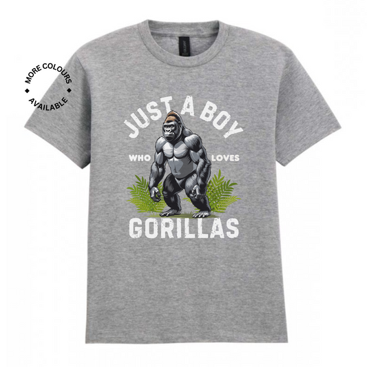 Kids sports-grey T-shirt with “Just a Boy Who Loves Gorillas” text and gorilla graphic over green leaves, flat lay on white background.
