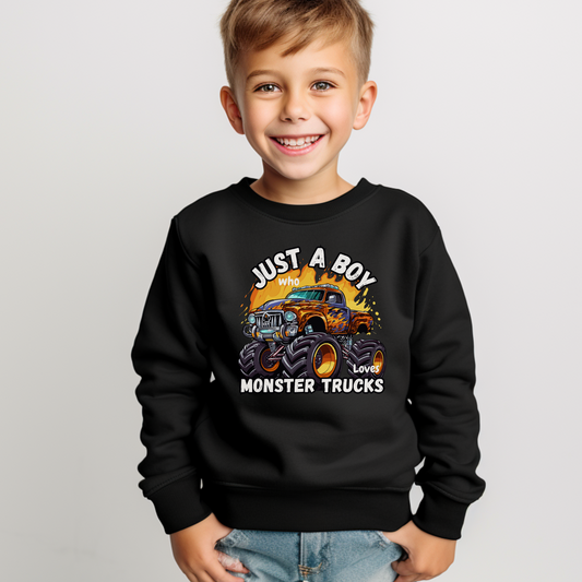 A young boy smiles in a studio while wearing a black sweatshirt with a printed design, Just a Boy who Loves Monster Trucks.