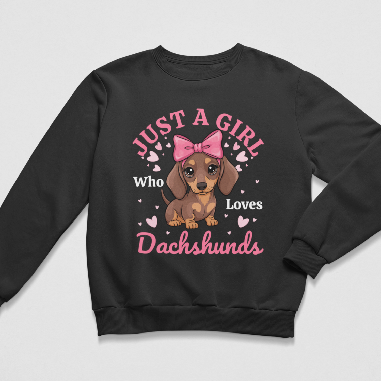 A kids black crewneck sweatshirt featuring a graphic print of a brown dachshund puppy with a pink bow, surrounded by pink hearts and the text 'JUST A GIRL Who Loves Dachshunds' in pink and white.