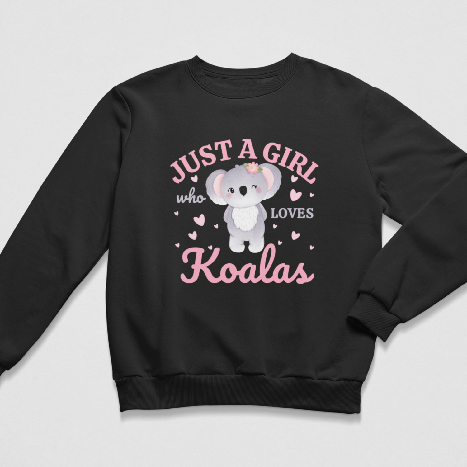A kids black crewneck sweatshirt featuring a cute cartoon koala graphic and the text 'JUST A GIRL who LOVES Koalas' in pink and white, displayed on a light grey background.