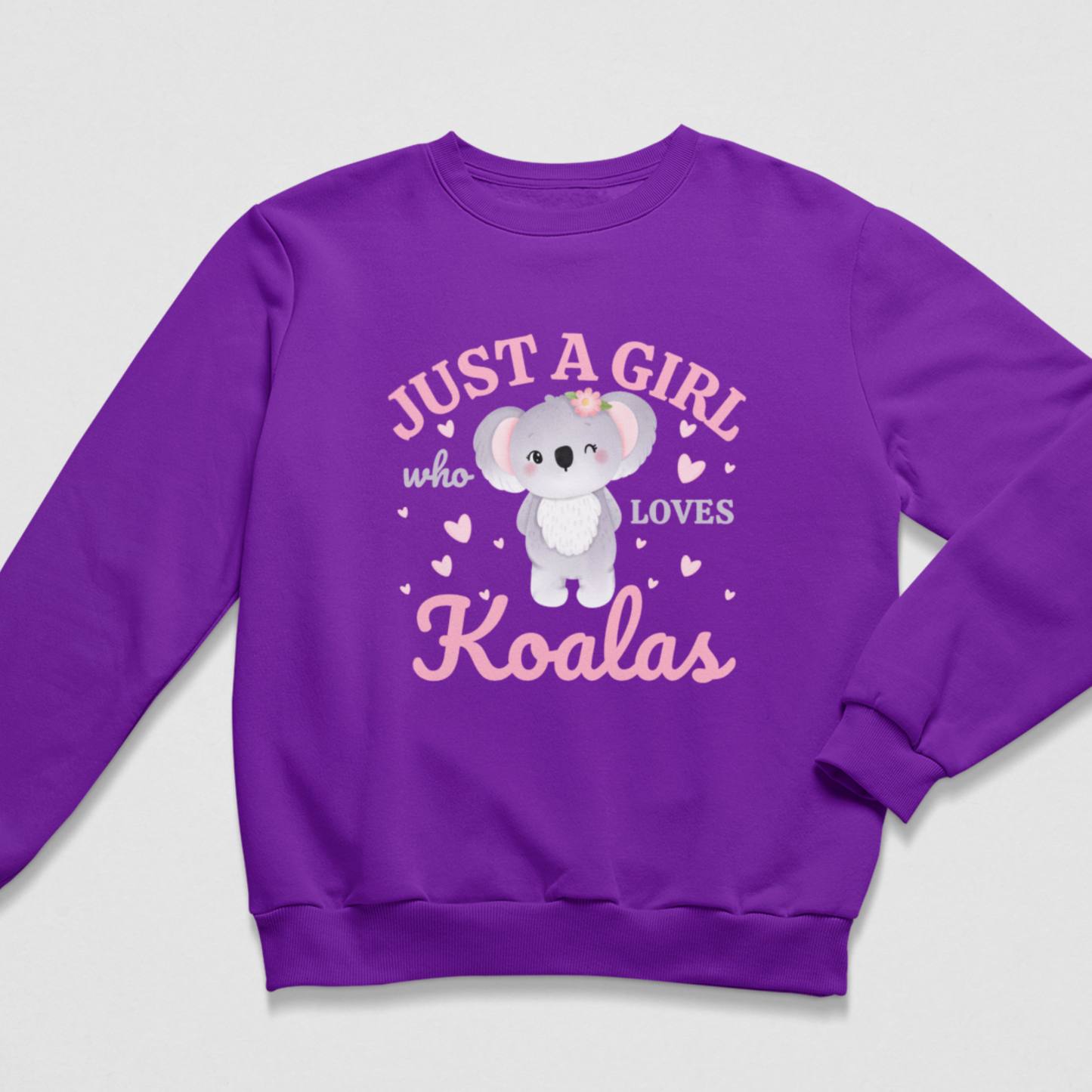 A kids purple crewneck sweatshirt featuring a cute cartoon koala graphic and the text 'JUST A GIRL who LOVES Koalas' in pink and grey, displayed on a light grey background.