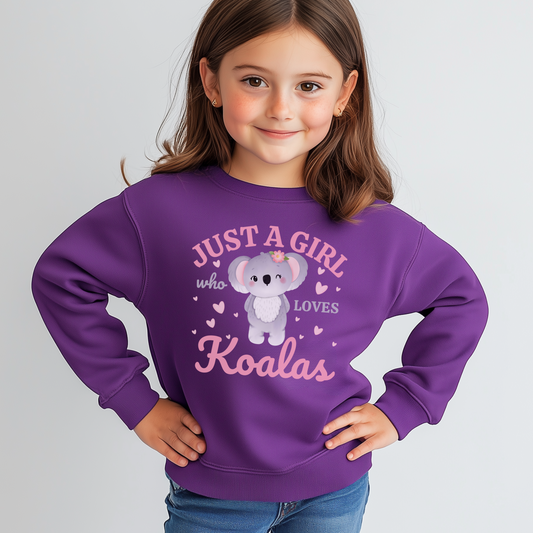 A young girl modelling a purple sweatshirt featuring a printed design of a cute cartoon koala surrounded by pink hearts, with the words “Just A Girl Who Loves Koalas” written above and below in playful text.