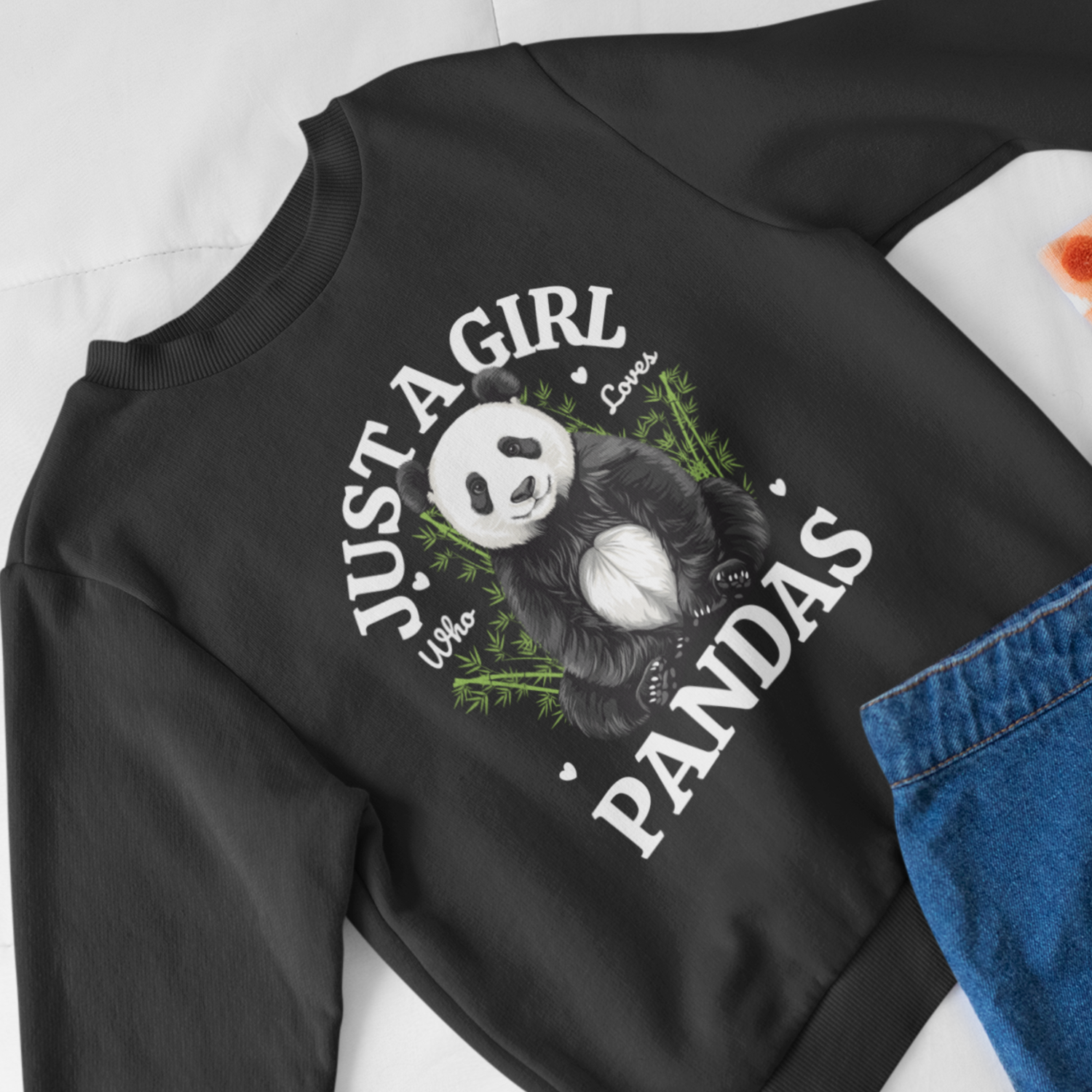 Girls black sweatshirt with "Just A Girl Who Loves Pandas" slogan and cute panda graphic - styled with denim skirt.