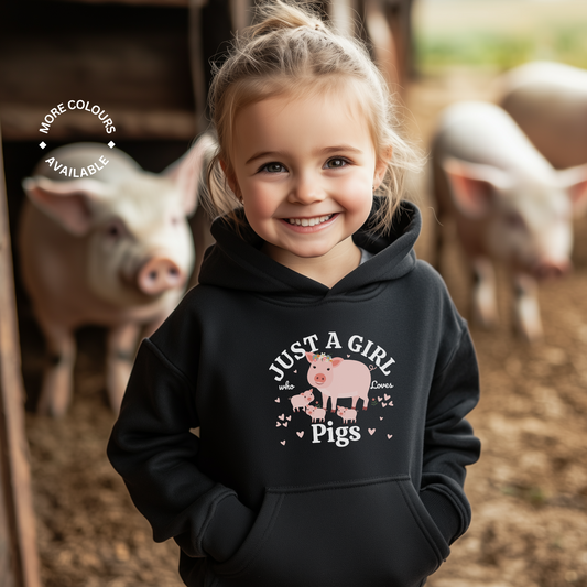 Young girl wearing a black hoodie with a pig design and text, standing in front of pigs on a farm.