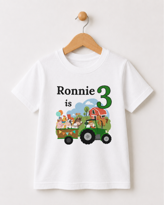 Personalised kids farm tractor birthday T-shirt with name and age, displayed on a wooden hanger.