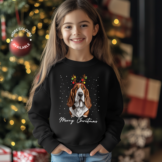 A child wearing a black sweatshirt with a graphic of a Basset Hound dog wearing festive antlers and the text 'Merry Christmas'.
