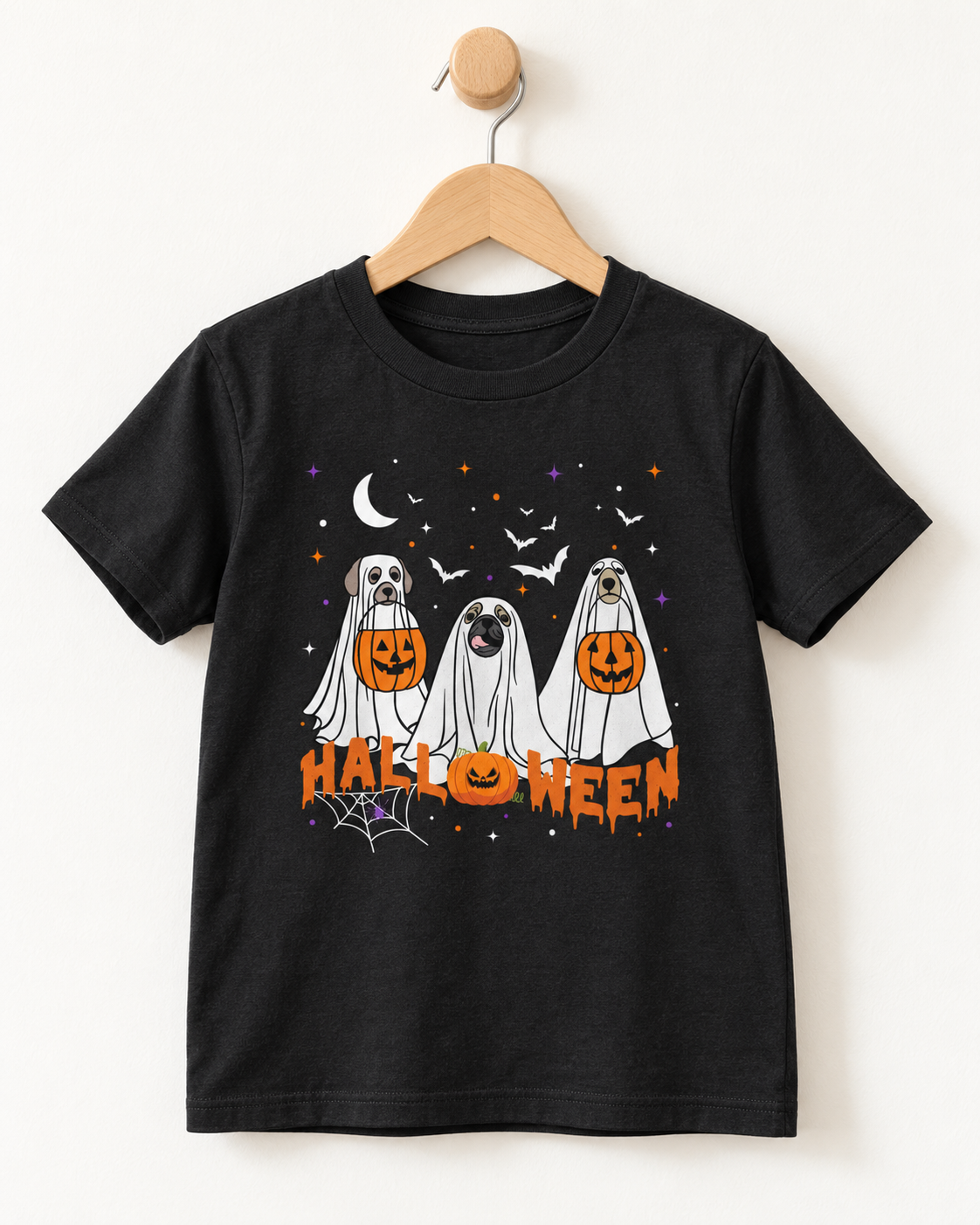 Kids’ black Halloween T-shirt on a wooden hanger featuring three dogs dressed as ghosts, pumpkin buckets, bats and orange “Halloween” lettering.