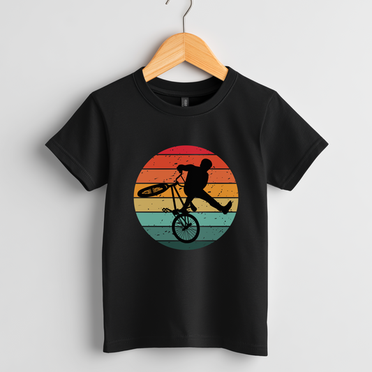 Kids black t-shirt on a wooden hanger features a colourful graphic of a silhouette doing a stunt on a BMX bike