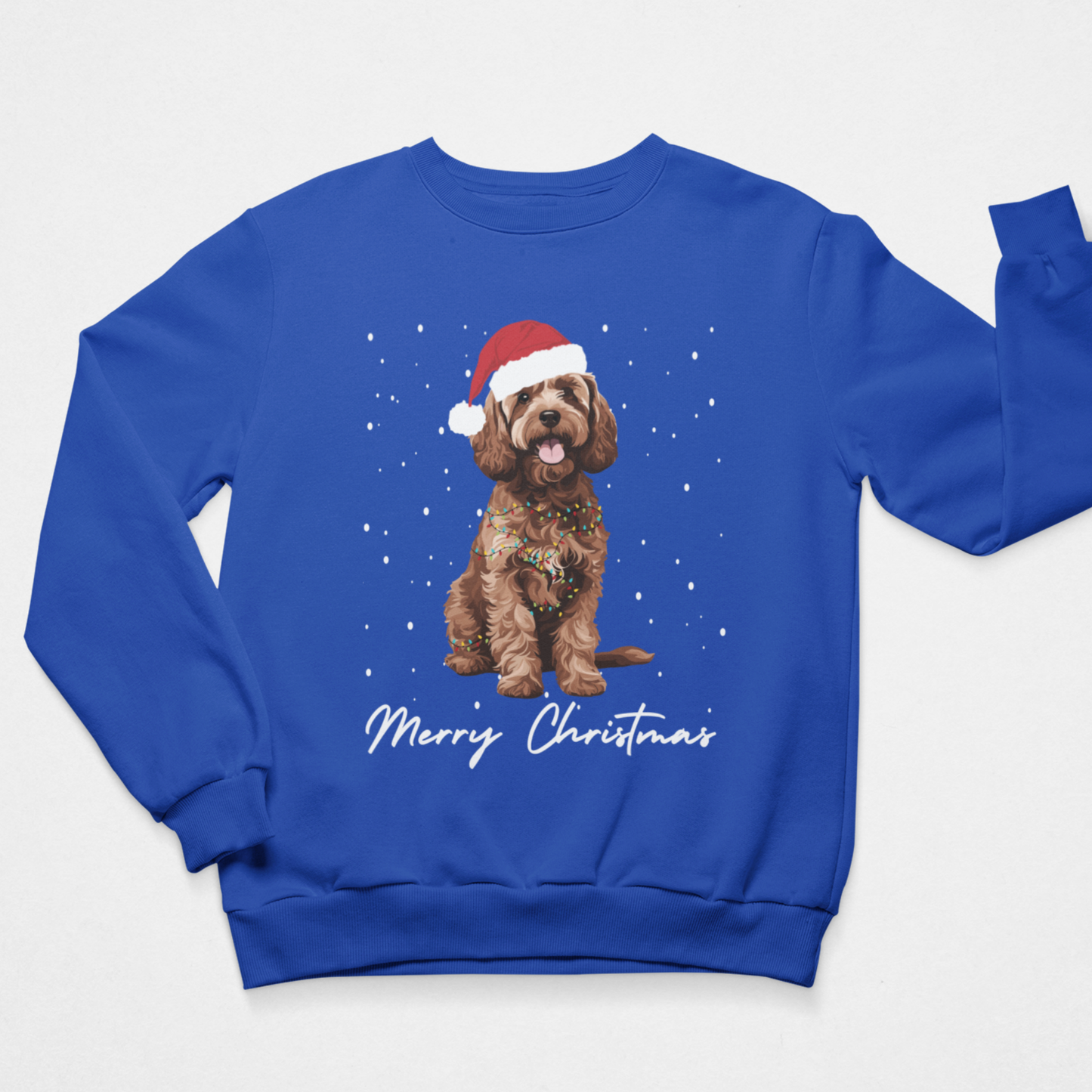 A kids royal blue crewneck sweatshirt featuring a graphic of a brown curly-haired cockapoo dog wearing a red Santa hat, surrounded by white snowflakes, with 'Merry Christmas' written in white script below. The sweatshirt is displayed flat against a light grey background.