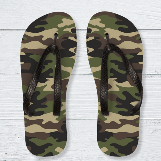 Kids camouflage flip-flops with textured black straps, shown on a white wooden background with an olive green, khaki, brown and black camo pattern.