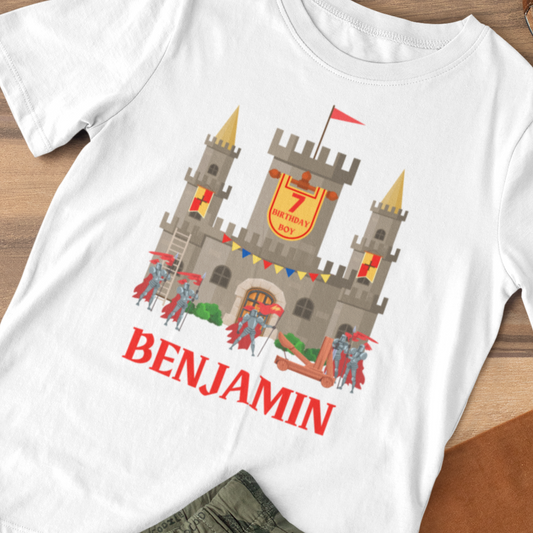 Boys white birthday T-shirt featuring a medieval castle with gold turrets, knights, and a banner reading “7 Birthday Boy,” personalised with the name “Benjamin”