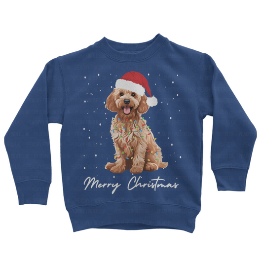 Kids royal blue sweatshirt with a Christmas-themed design of a golden cockapoo wearing a Santa hat, wrapped in fairy lights with falling snow and the text 'Merry Christmas'.
