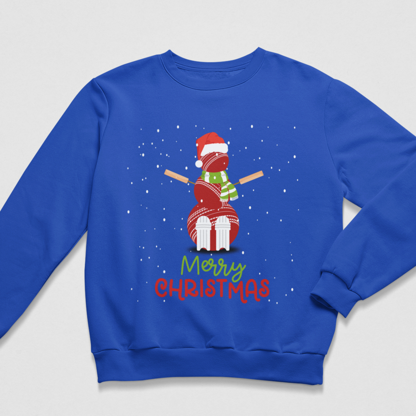 A kids royal blue crewneck sweatshirt featuring a festive graphic of a cricket ball snowman, with 'Merry Christmas' written below in colourful text against a light grey background.