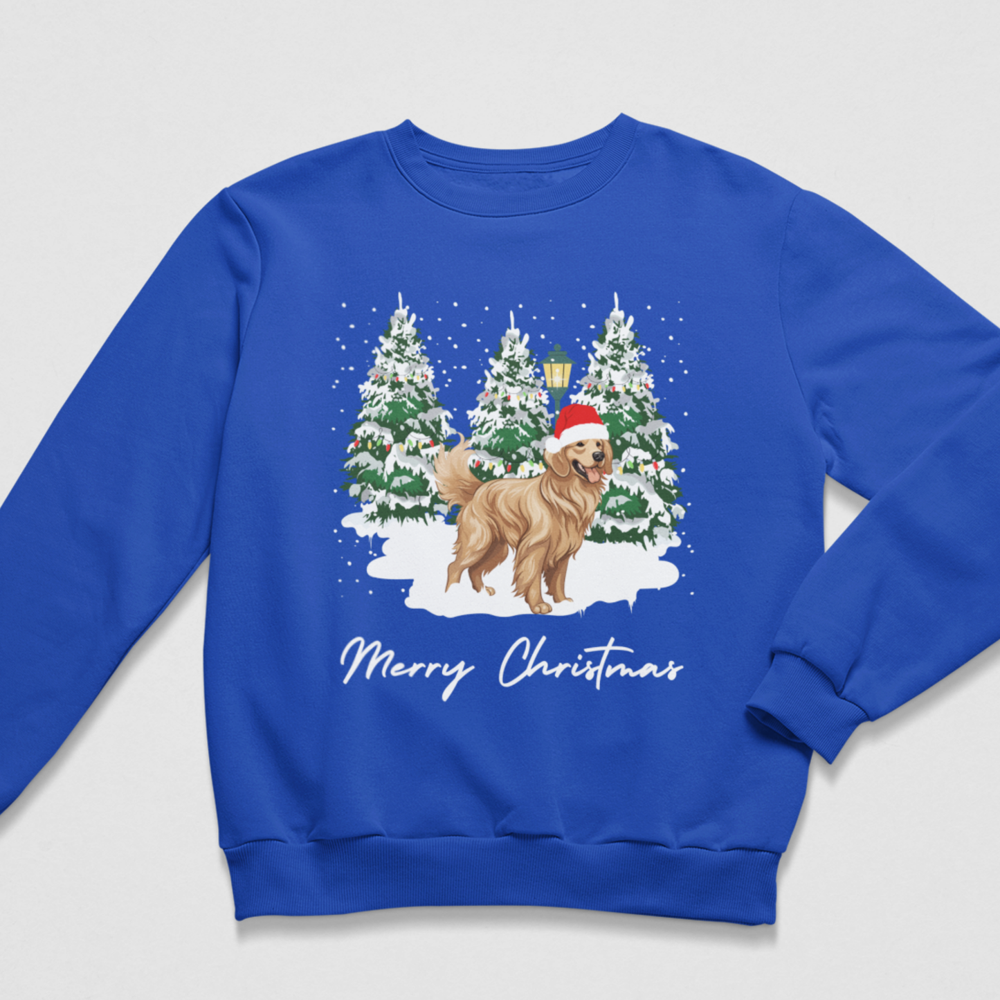 A kids royal blue crewneck sweatshirt featuring a festive Christmas graphic of a golden retriever dog wearing a Santa hat, standing in front of snow-covered pine trees. Below the illustration, the text 'Merry Christmas' is printed in white script.