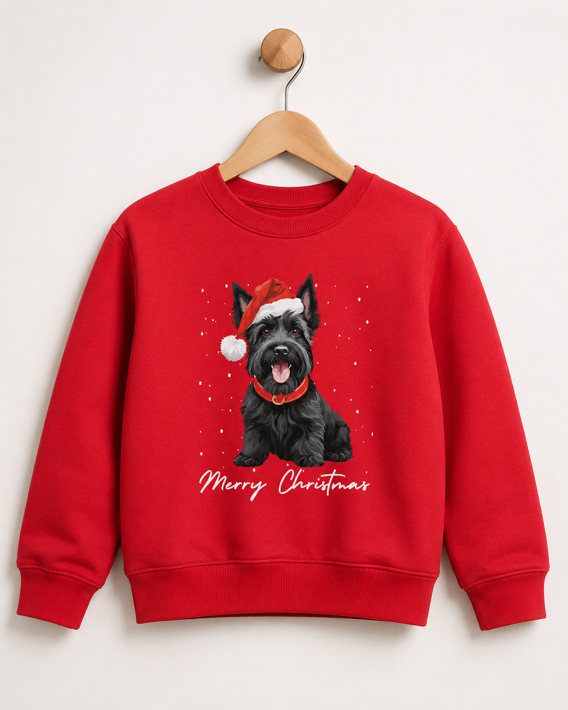 Children's red crewneck sweatshirt hanging on a wooden hanger against a light grey background. The sweatshirt features a graphic of a black Scottish Terrier wearing a Santa hat, with 'Merry Christmas' written in white script below.